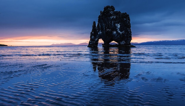 Photo is a spectacular rock in the sea on the northern coast of iceland legends say it is a petrified troll on this photo hvitserkur reflects in the sea water after the midnight sunset