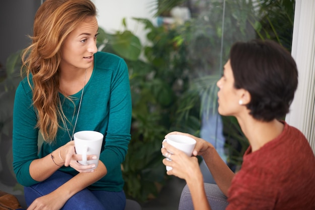 Так ли это? Снимок двух женщин-профессионалов, обсуждающих за чашкой кофе в неформальной обстановке офиса.