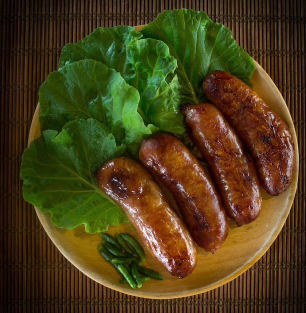 Isaan sausage or Thai Northeastern sausage pork and rice sausages Sai Krok Isan on wood plate with cabbage and chilli