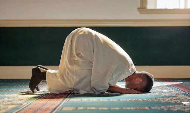 Foto religione islamica e preghiera di un uomo musulmano alla moschea del ramadan per la fede spirituale dio e credenza durante il culto religioso persone di cultura islamica o araba sedute a pregare in un luogo santo