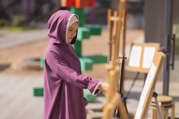 Islamic beautiful woman in a Muslim dress standing on a summer park street background forest autumn trees.world hijab day.