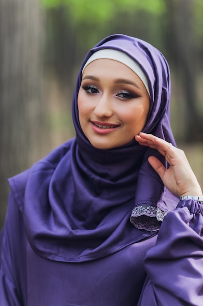 Islamic beautiful woman in a Muslim dress standing on a summer park street background forest autumn trees.world hijab day.