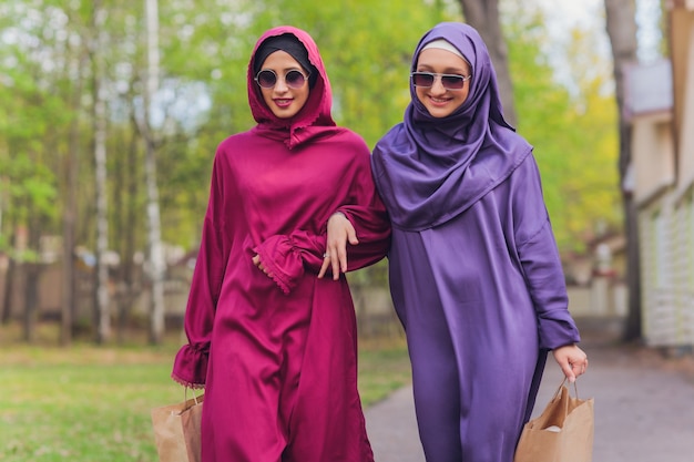 Islamic beautiful woman in a Muslim dress standing on a summer park street background forest autumn trees.world hijab day.