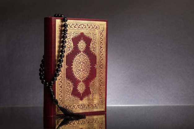 Islamic Book Koran with rosary on grey background