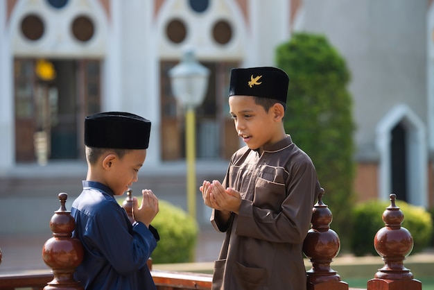 An Islamic child prays to study with his sister and brother in a mosque in Songkhla, Thailand.