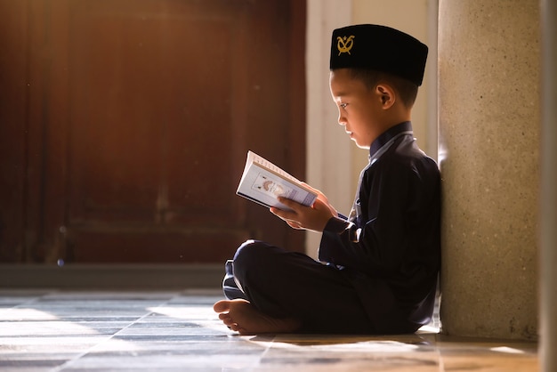 An Islamic child prays to study with his sister and brother in a mosque in Songkhla, Thailand.