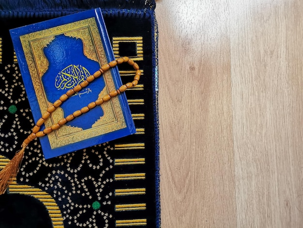 Islamic concept. Al Quran and rosary beads on prayer mat. Selective focus.