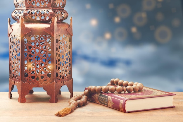 Islamic holy book quran with rosary beads and ornamental arabic\
lantern with burning candle glowing