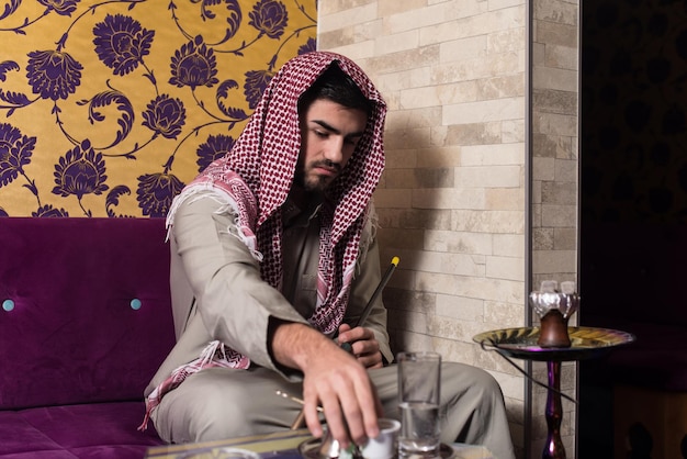 写真 コーヒーを飲みながら伝統的なハッブルバブルまたは水ギセルを吸うイスラム教徒の男