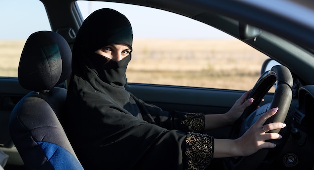 Islamic woman taxi driver driving a car.,