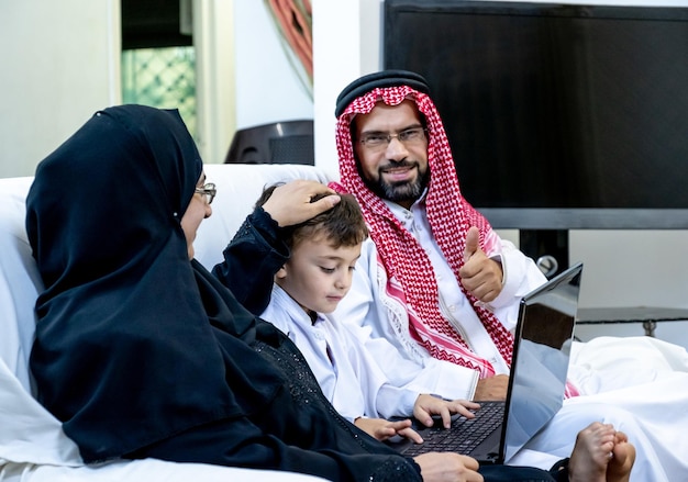 Islamitische Arabische jongen die zijn ouders zijn laptop laat zien en zijn werk erop