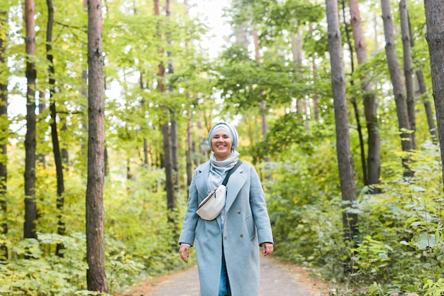 Islamitische jonge vrouw die hijab draagt die zich op de achtergrond van het herfstpark modern Arabisch moslimmeisje bevindt