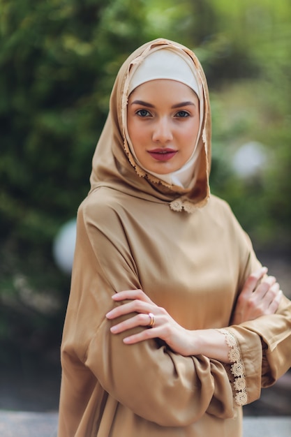 Islamitische mooie vrouw in een moslim jurk staande op een zomer park straat achtergrond bos herfst bomen