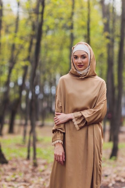 Islamitische mooie vrouw in een moslim jurk staande op een zomer park straat achtergrond bos herfst bomen