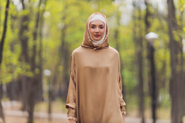 Islamitische mooie vrouw in een moslim jurk staande op een zomer park straat achtergrond bos herfst bomen