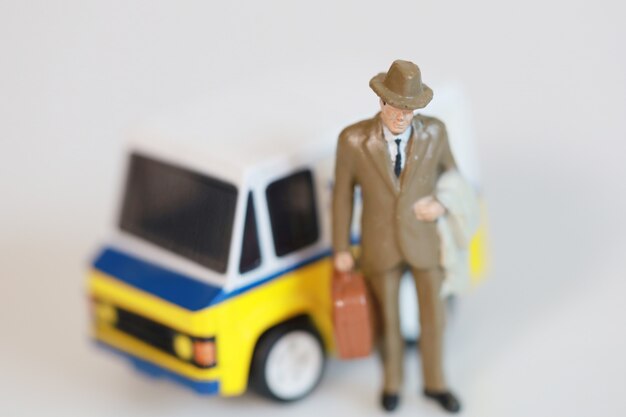 Isolate Toy businessman are standing near mini van car for go to working with van car on white