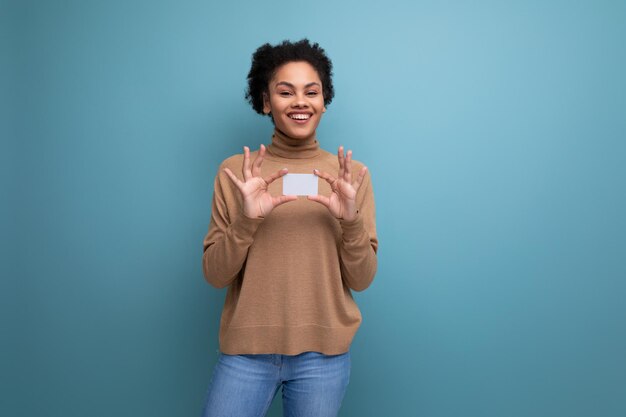 Isolated background cute young brunette hispanic woman with ponytail hairstyle holding credit card