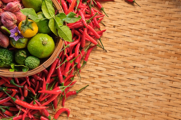 Isolated banner left side of thai traditional food ingredients in basket, dry chilies, small red onions, lime, and thai vegetable, layout laying on wooden thai traditional rack wood pattern