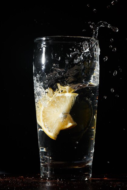 Isolated on a black background a glass of water with lemon