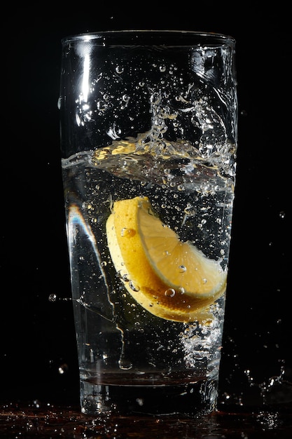 Isolated on a black background a glass of water with lemon