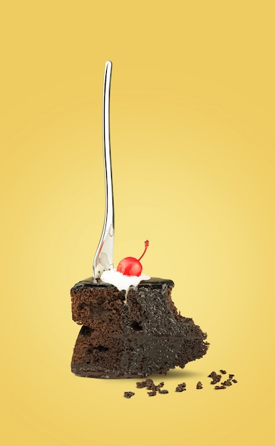 Isolated Chocolate cherry cake with fork from back on yellow background.
