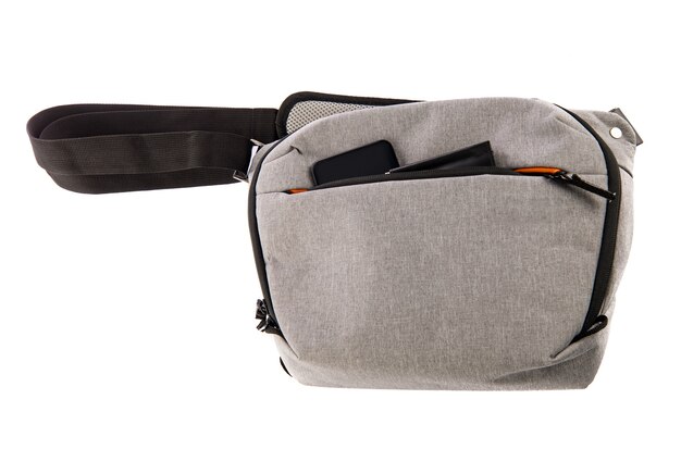 Photo isolated close up studio shot of small photographer modern fashionable gray shockproof waist bag soft compartment fanny pack carry smartphone and wallet in front zipper pocket on white background.