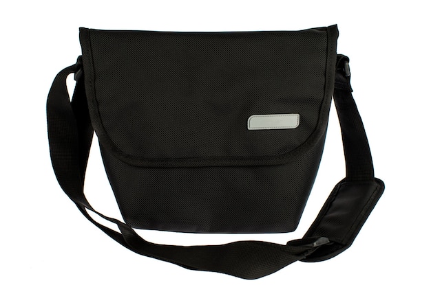 Isolated closeup studio shot of new small casual modern trendy fashionable fabric black messenger rider men sling bag handbag baggage with strap and gray empty label tag in front of white background.