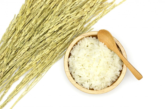 白い背景の上の米の耳を持つ木製のボウルで調理ジャスミンライスを分離