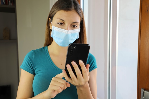 Isolated girl with mask and smart phone at home.