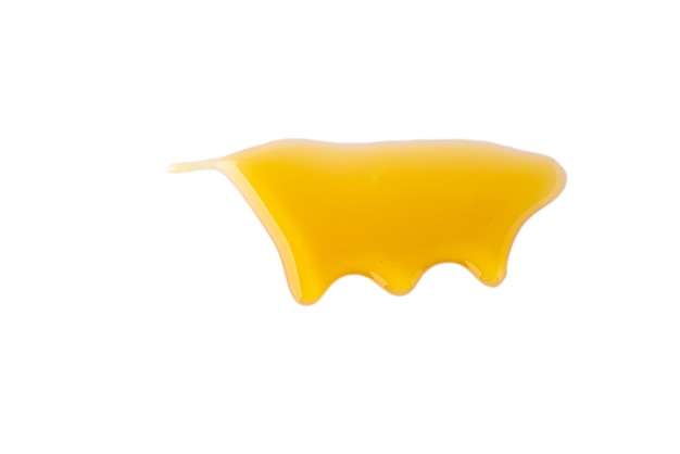 Isolated gold honey melting on white background sticky yellow dense liquid flowing horizontal