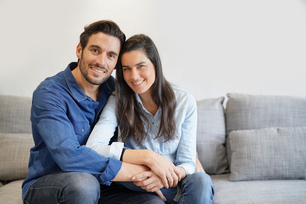 Isolated gorgeous smiling couple in denim on comfy couch