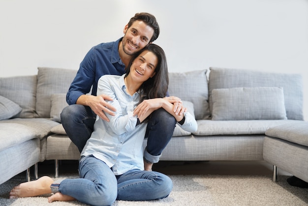 Isolated gorgeous smiling couple in denim on comfy couch