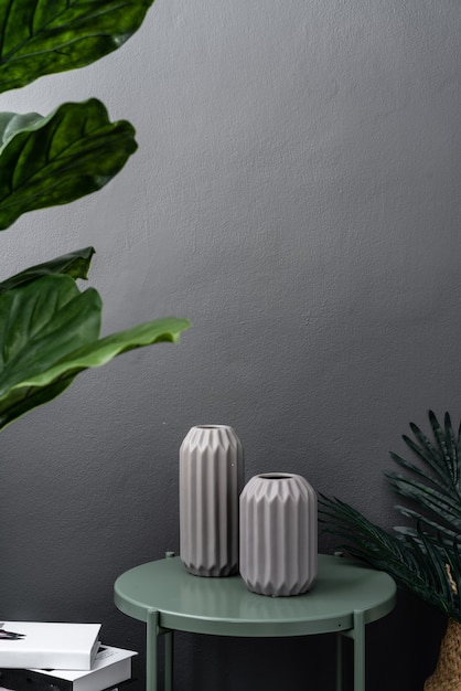 Isolated gray ceramic vase on green metal side table on gray painted wall