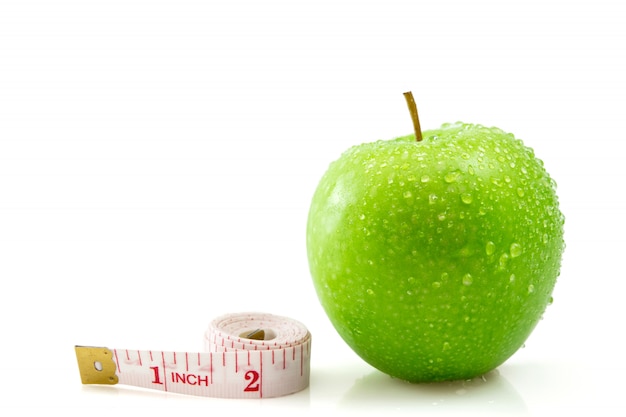 Фото Изолированное зеленое яблоко с измеряя лентой на белизне, концепция здоровой и диета.