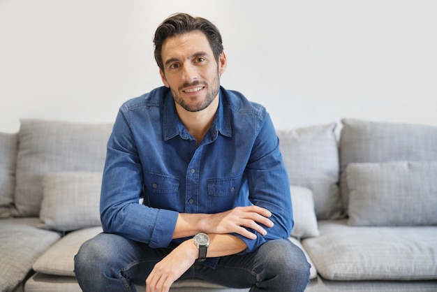 Isolated handsome man in denim on comfortable couch