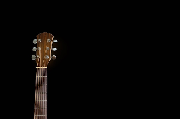 Isolated head of acoustic guitar leaned against the dark blackbackground