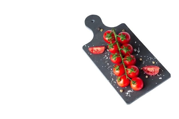 Isolated image of fresh bright cherry tomatoes on a cutting board with salt and pepper