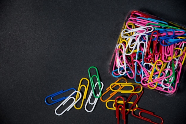 Isolated multicolored paper clip on black background Blackspace for your text