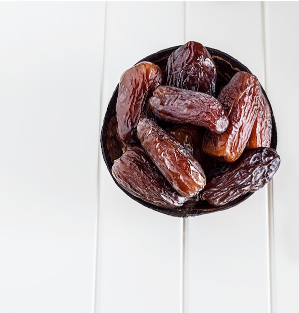 Isolated Organic Dates Medjul in coconut bowl on white background. 