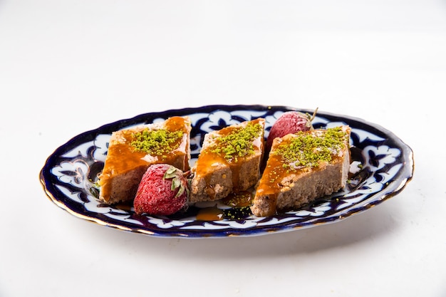 Isolated oriental sweetness baklava with honey and pistachios on the traditional plate