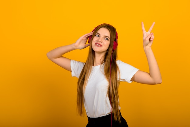 Isolated portrait of happy woman has toothy smile, closes eyes, feels pleasure from good compliment, stands on yellow wall.