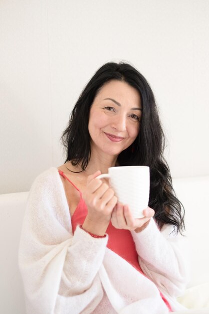 An isolated serene woman with black hair is enjoying a warm drink embodying the calm acceptance of midlife hormonal changes and menopause