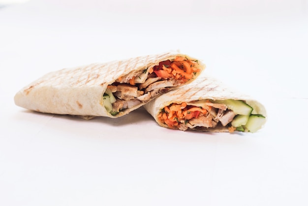 Foto shawarma isolato con un'ombra. cibo orientale a base di carne di pollo, pomodori, cetrioli nel pane pita