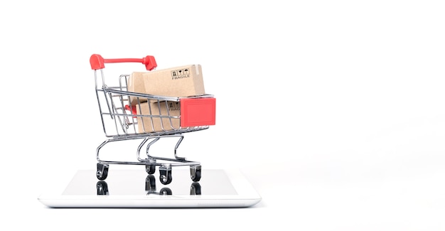 Isolated of Shipping paper boxes inside Red shopping cart trolley on tablet with white background and copy space , Online shopping and e-commerce concept.