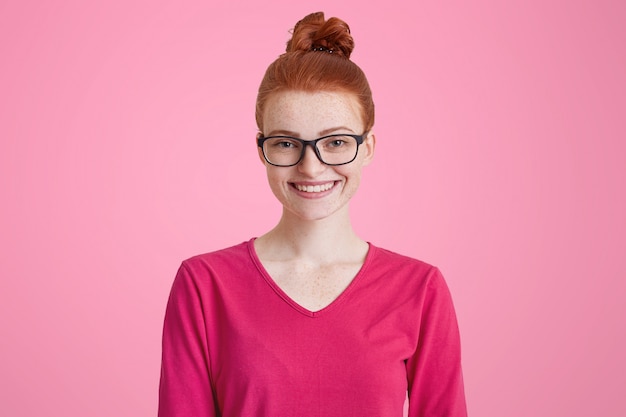 Isolated shot of happy ginger woman in pink sweater