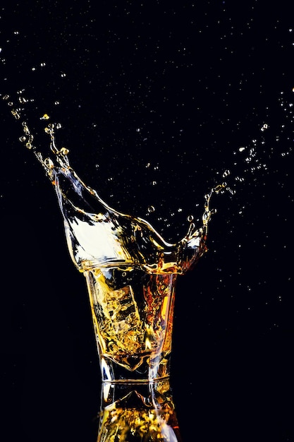 Photo isolated shot of whiskey with splash on black background brandy in a glass