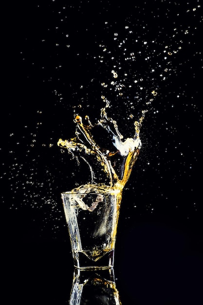 Isolated shot of whiskey with splash on black background brandy in a glass