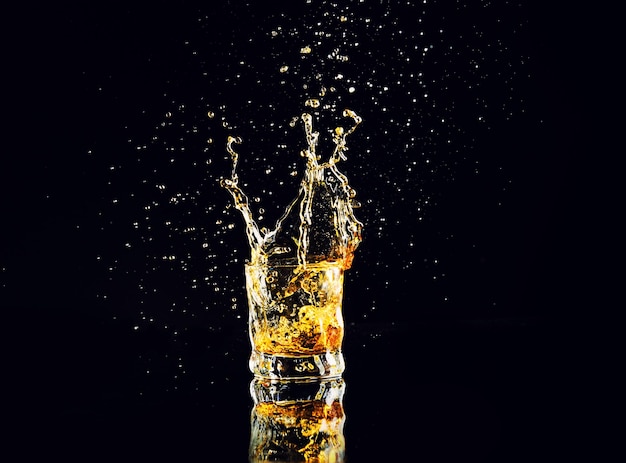 Isolated shot of whiskey with splash on black background brandy in a glass