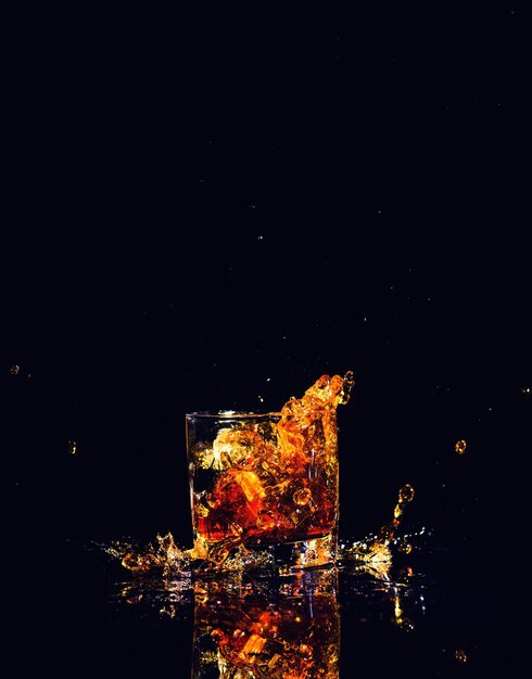 Isolated shot of whiskey with splash on black background brandy in a glass