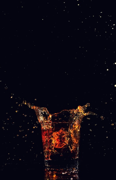 Photo isolated shot of whiskey with splash on black background brandy in a glass